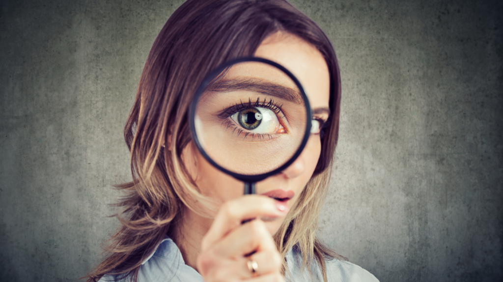 Woman holding magnifying glass in front of her eye